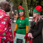 Isla (played by Isabella Gomez) and Kat (played by Laura Marano) talk to their ambitious boss Mr. Mujiza (played by Garfield Wilson) at Santa Land.