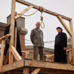 Rob Stewart as Andrew May Sr. and Darren Stewart as the Hanging Official in Slasher: Ripper (Season 5, Episode 2). Photo Credit: Nikki Ross /Shudder