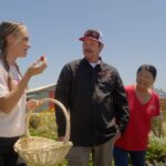 Dariany Santana holding a basket with strawberry in hand talking to Molly and Kristopher Gean