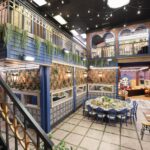 ‘Mystery Hotel Theme’ Set Plates of the Big Brother House for season 27 of the CBS Original Series BIG BROTHER, scheduled to air on the CBS Television Network.  Pictured: Rooftop Garden Kitchen: The kitchen and dining area mimic a rooftop garden with ivy-covered walls, sunset skies and a 10-foot round garden party table under string lights. Photo: Matthew Taplinger ©2025 CBS Broadcasting, Inc. All Rights Reserved.