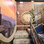 ‘Mystery Hotel Theme’ Set Plates of the Big Brother House for season 27 of the CBS Original Series BIG BROTHER, scheduled to air on the CBS Television Network.  Pictured: Rooftop Garden Kitchen: The kitchen and dining area mimic a rooftop garden with ivy-covered walls, sunset skies and a 10-foot round garden party table under string lights. Photo: Matthew Taplinger ©2025 CBS Broadcasting, Inc. All Rights Reserved.