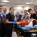 Medic Harley brings in Roxie; Medic Bashir brings in badly beaten Gus Varney. (Warrick Page/HBOMAX)